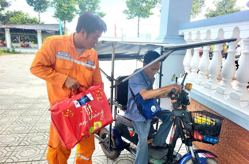 Nhân viên điện lực mang quà Tết tới tận xe cho những bà con có hoàn cảnh đặc biệt. Ảnh: PC Cần Thơ